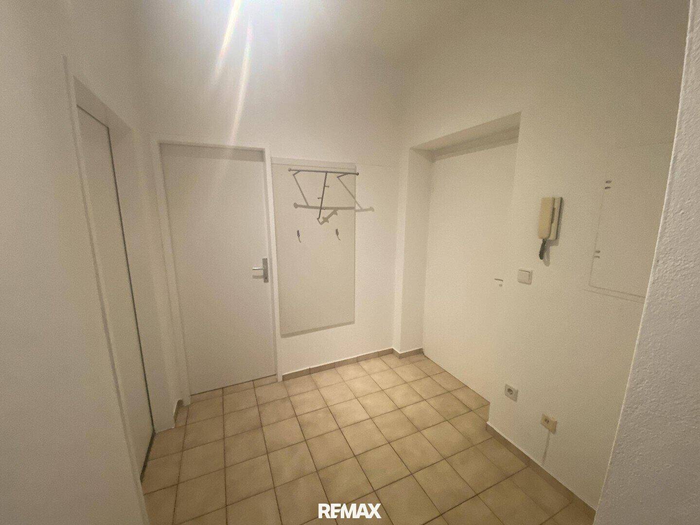 Eingangsbereich mit Fliesenboden, Garderobe und Gegensprechanlage, hell und funktional.