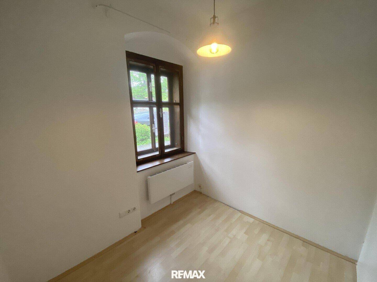Helles Zimmer mit Parkettboden und einem Fenster, ideal als Arbeits- oder Gästezimmer.
