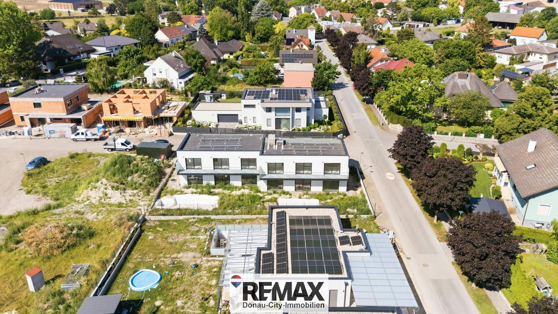 Luftaufnahme einer modernen Wohnanlage mit Solaranlagen und umliegender Bebauung.