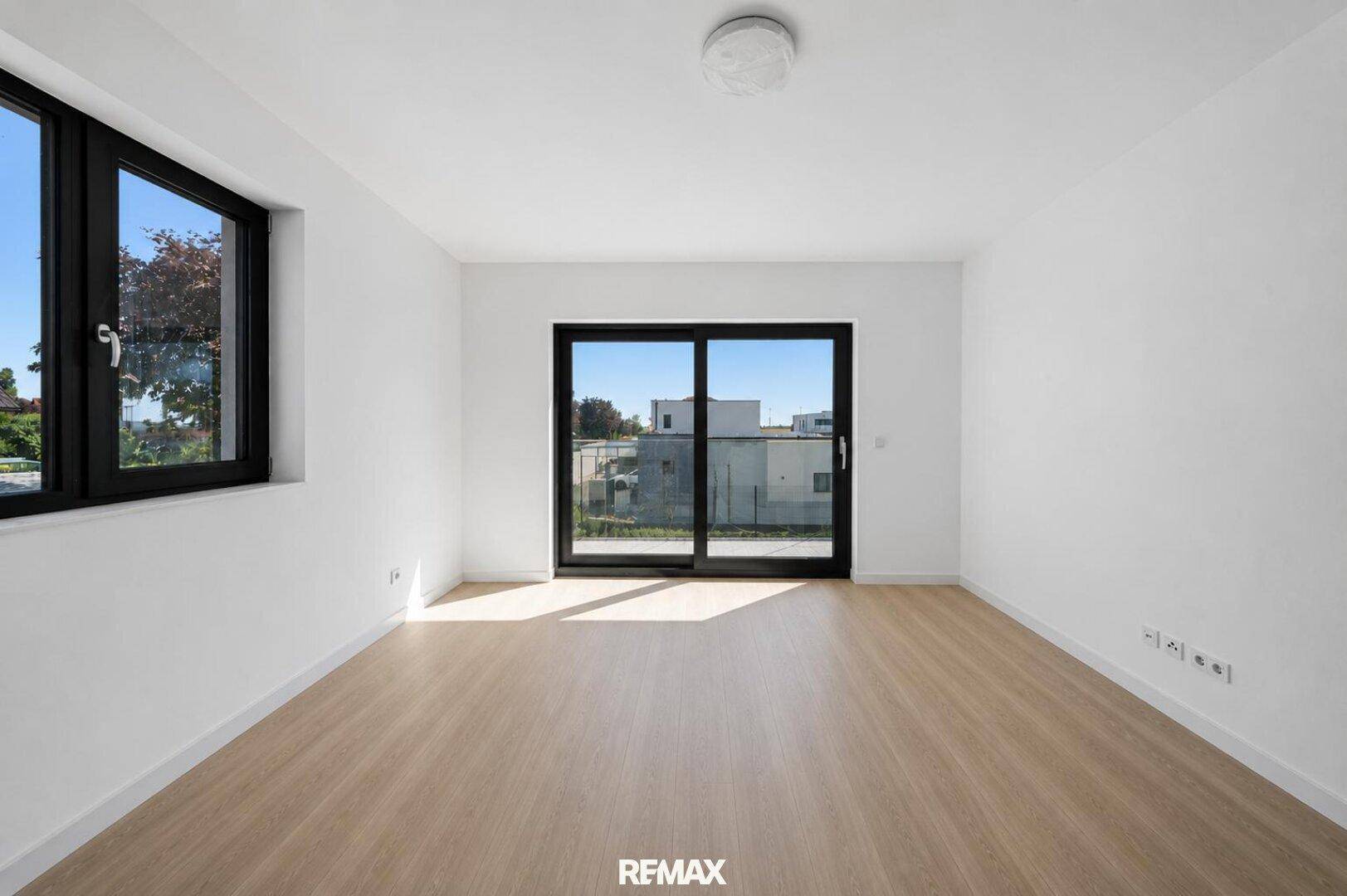Heller, leerer Raum mit Holzboden und Schiebetür zu einem französischen Balkon.
