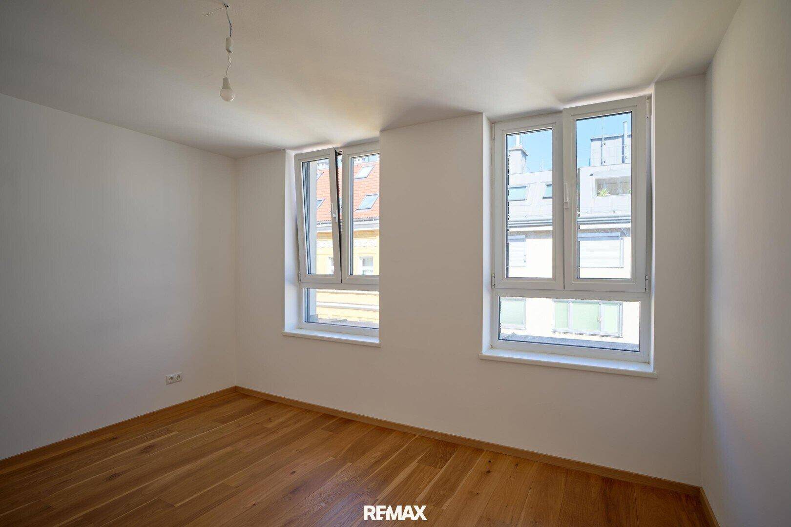 Helles Zimmer mit Parkettboden und zwei Fenstern, ideal als Schlaf- oder Arbeitszimmer.