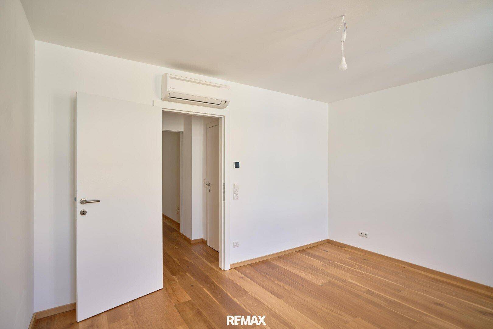 Geräumiges Zimmer mit Parkettboden und Klimaanlage, mit Zugang zu einem weiteren Bereich.