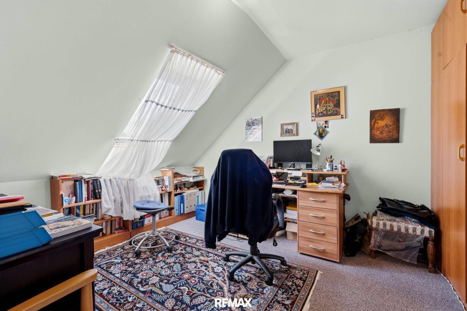 Helles Arbeitszimmer im Dachgeschoss mit Schreibtisch, Büchern und schrägen Decken für konzentriertes Arbeiten.