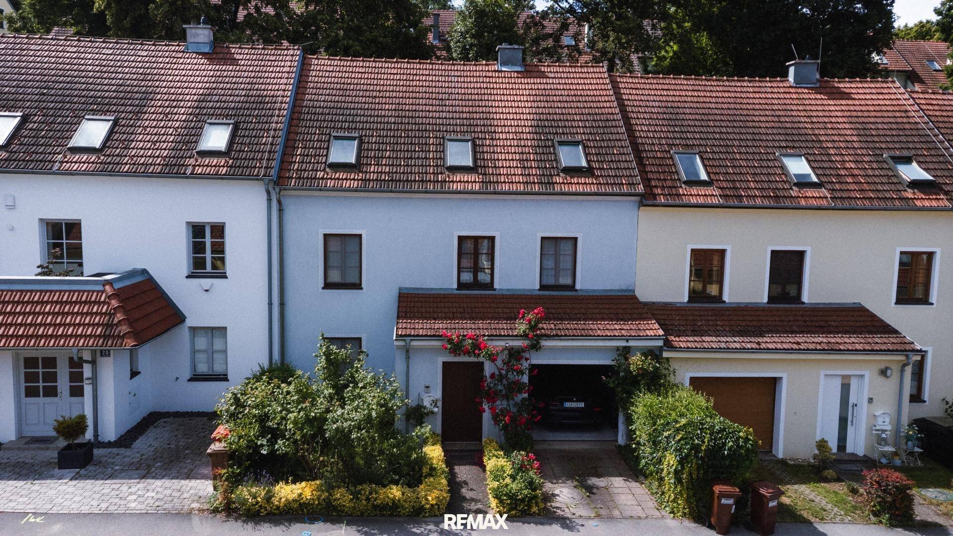 Reihenhäuser mit roten Ziegeldächern und kleinen Vorgärten in einer ruhigen Wohngegend.