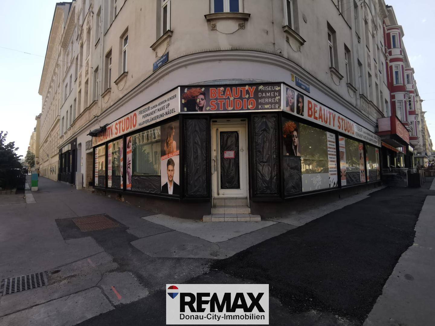 Eckgebäude mit einem "Beauty Studio" im Erdgeschoss, umgeben von einer belebten Straße.