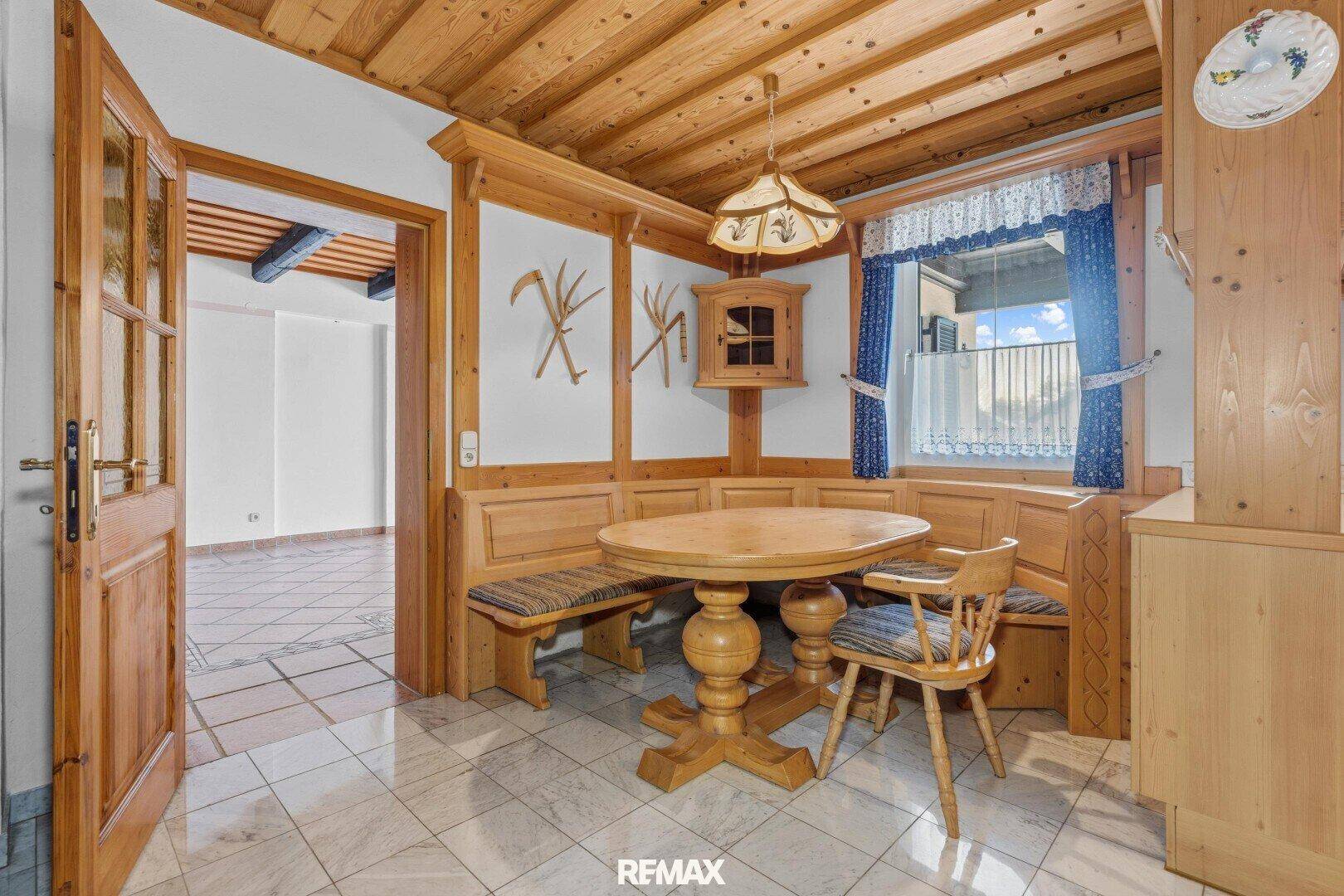 Traditioneller Essbereich mit Holzbänken und Tisch, direkt an eine Küche angrenzend.