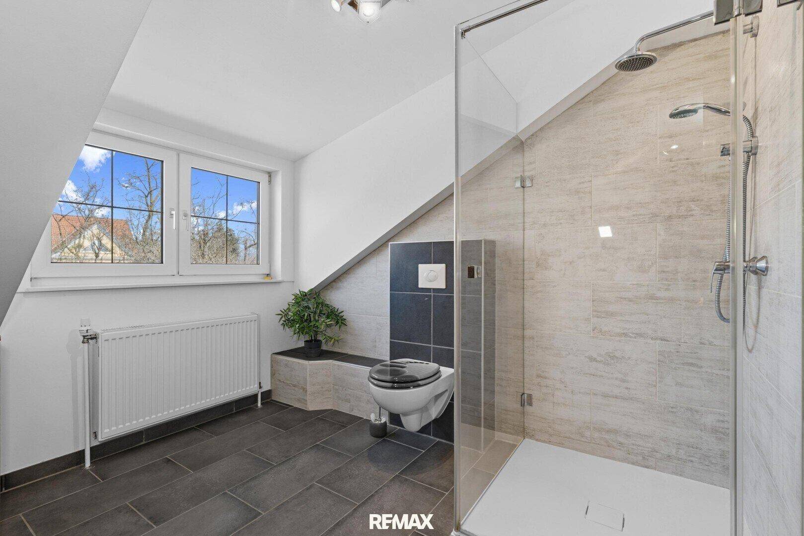 Modernes Badezimmer mit begehbarer Dusche, Wand-WC und Fenster unter Dachschräge.