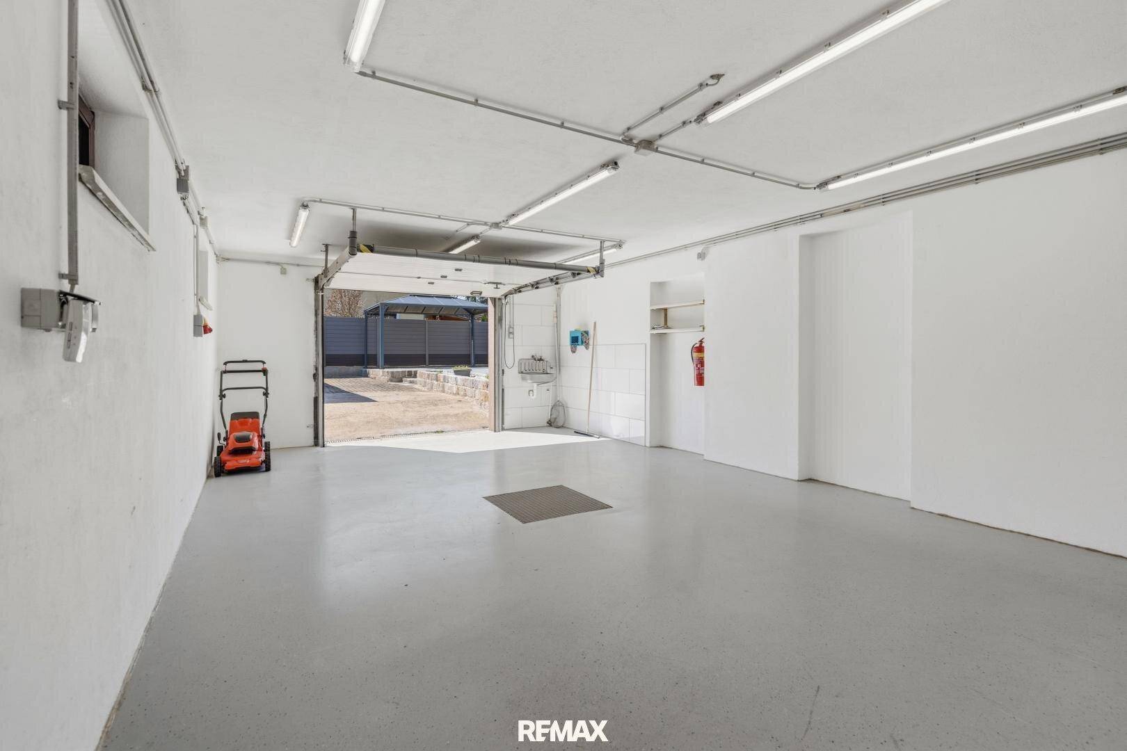Geräumige Garage mit Betonboden, Rolltor und ausreichend Platz für Fahrzeuge und Lagerung.
