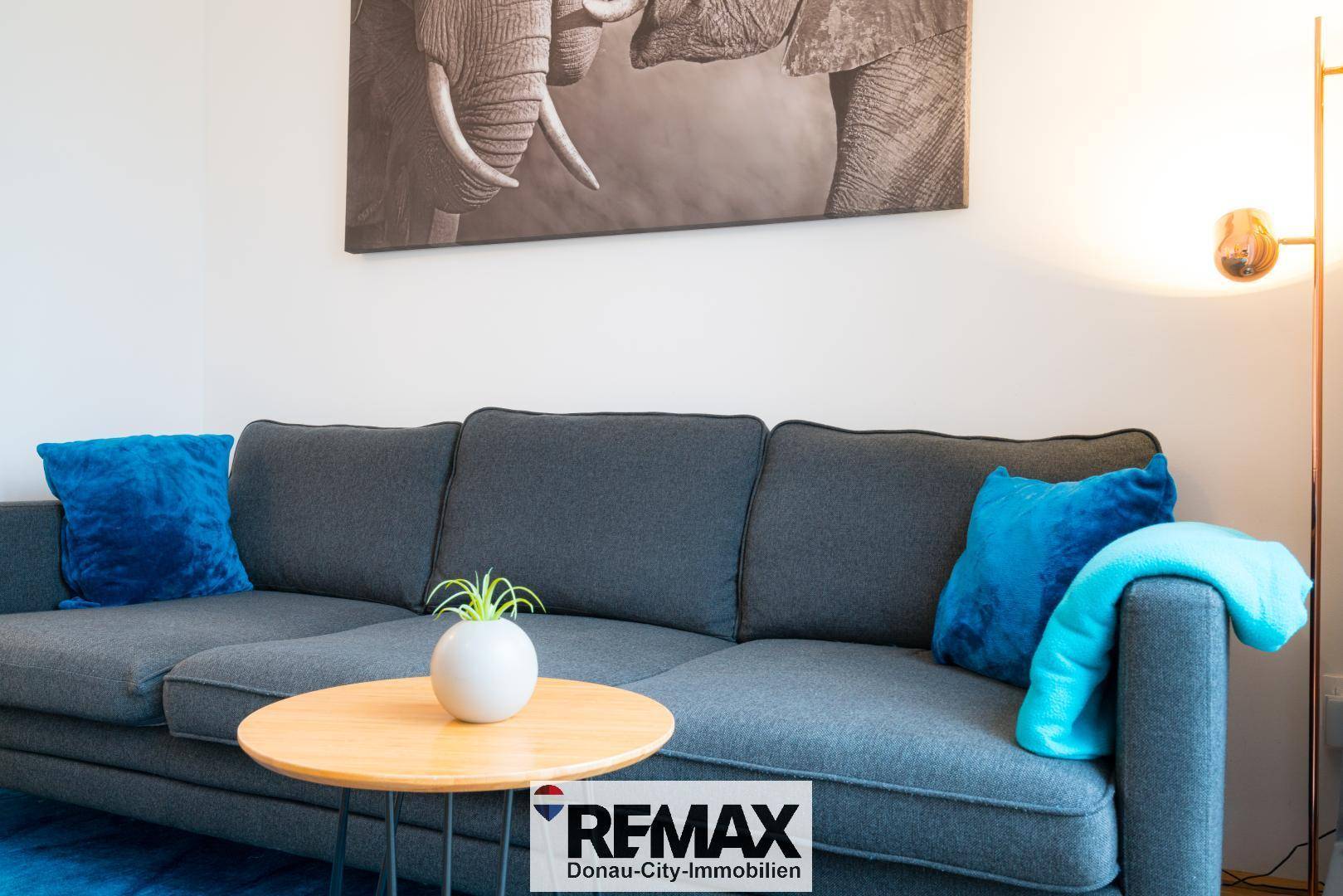 Detailansicht des modernen Sofas mit blauen Kissen und einem Beistelltisch im Wohnzimmer.