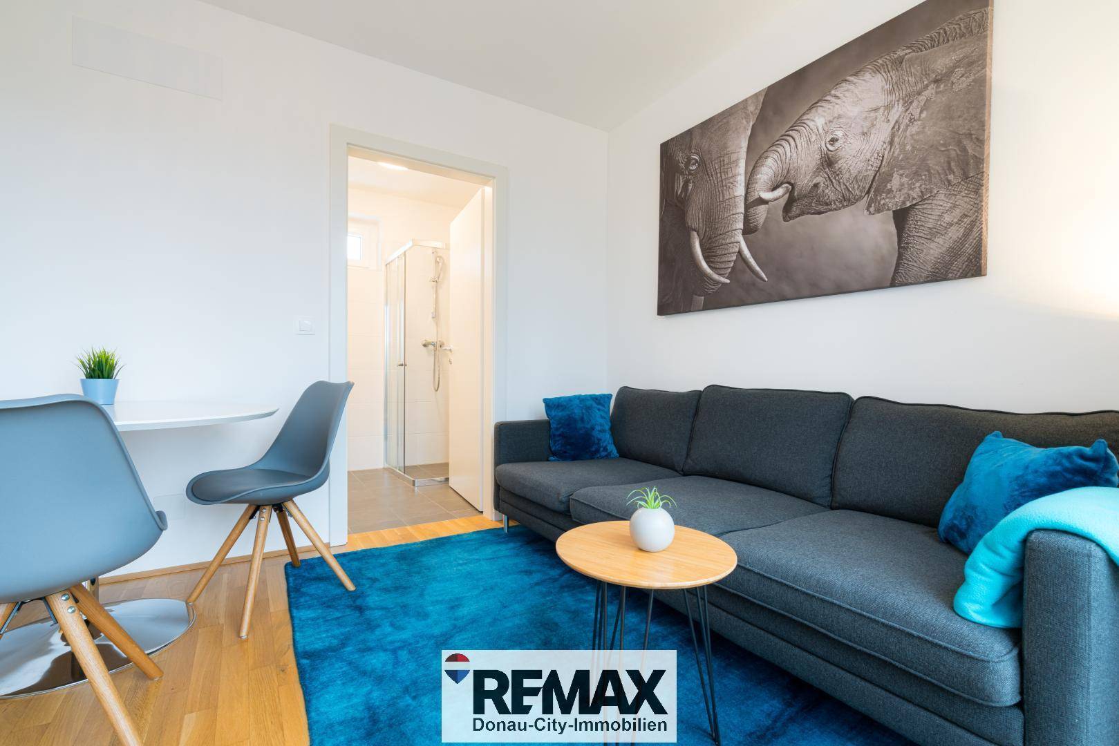 Heller Wohn- und Essbereich mit Sofa und Esstisch, angrenzend an das Badezimmer.