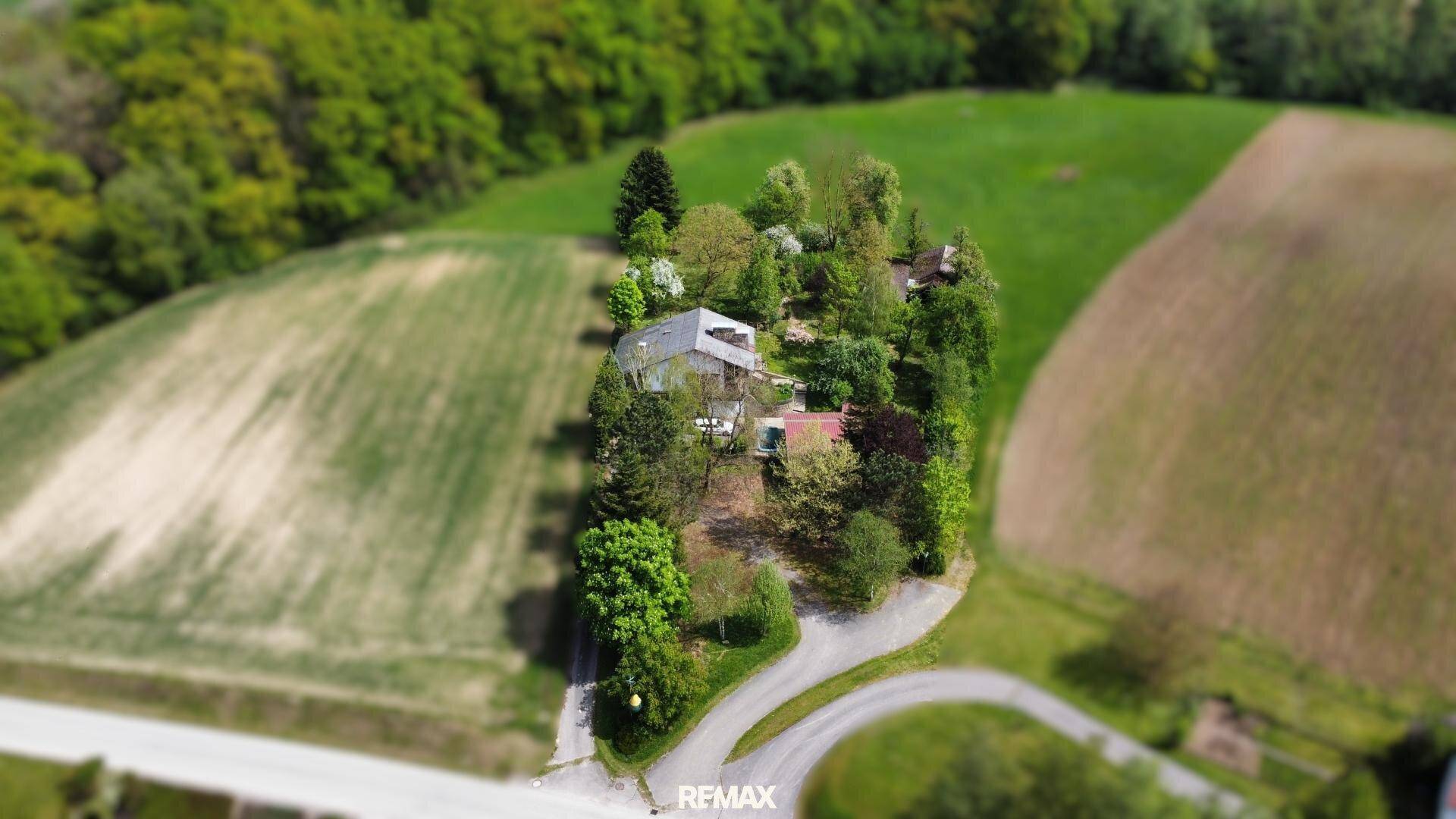 Vogelperspektive des Anwesens mit Haus, Garten und umliegenden Feldern.