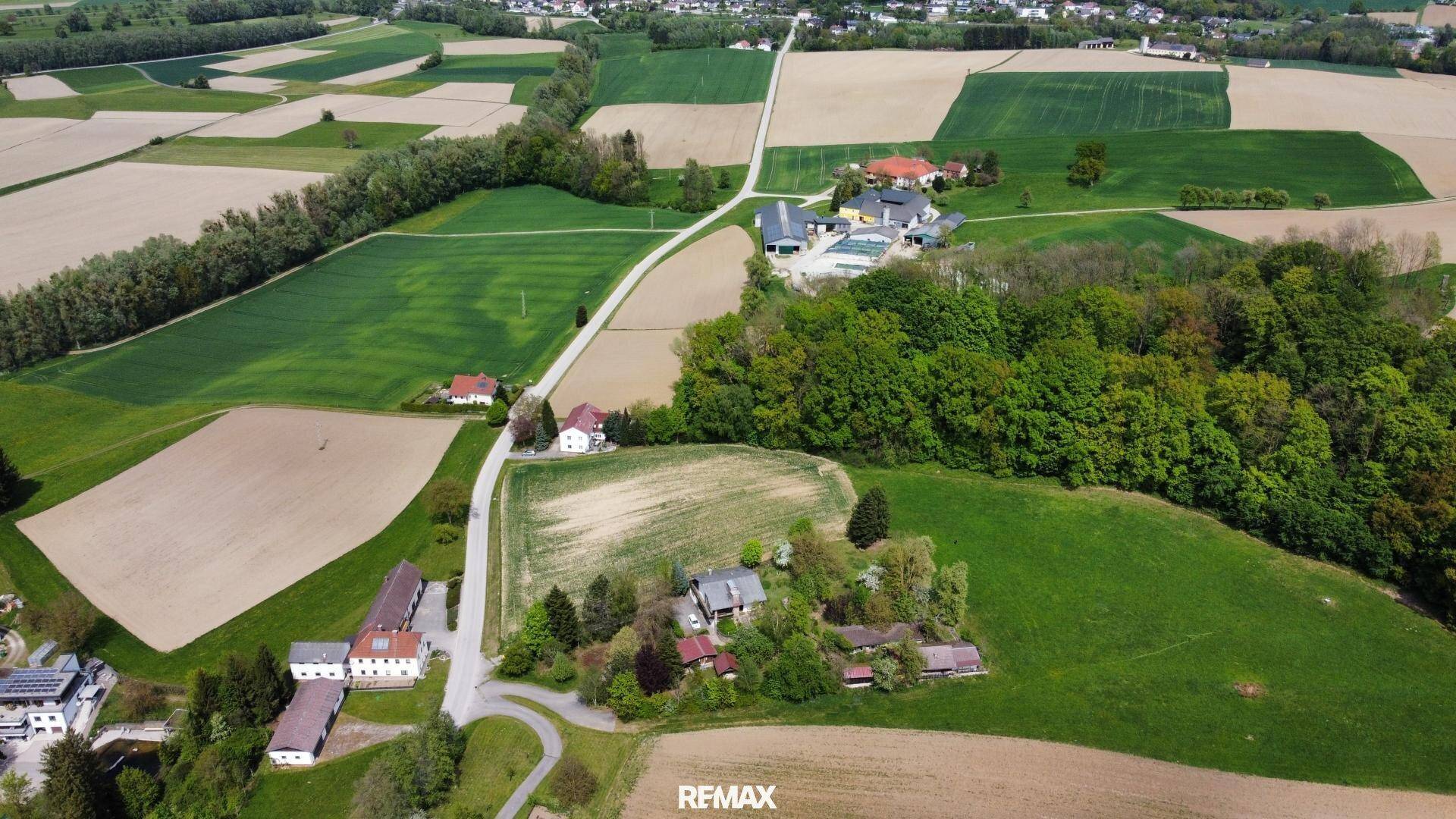 Weitläufige Luftaufnahme der ländlichen Umgebung mit Feldern und vereinzelten Häusern.
