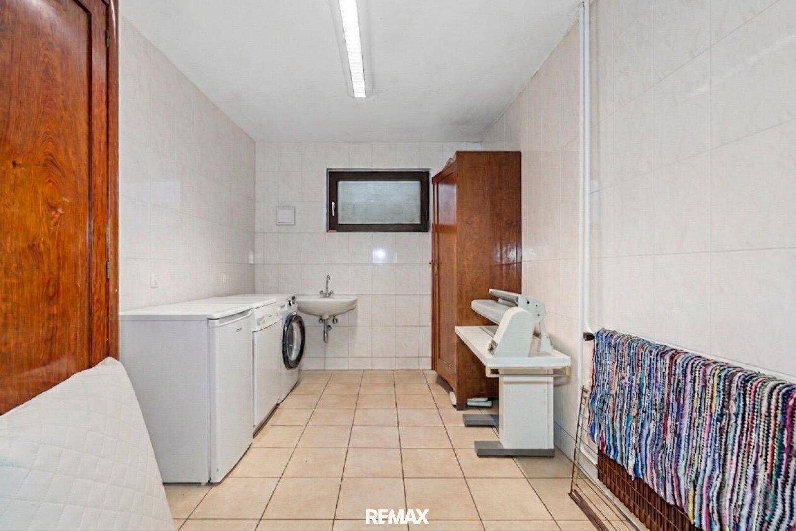 Praktischer Hauswirtschaftsraum mit Waschmaschine, Trockner und Waschbecken.