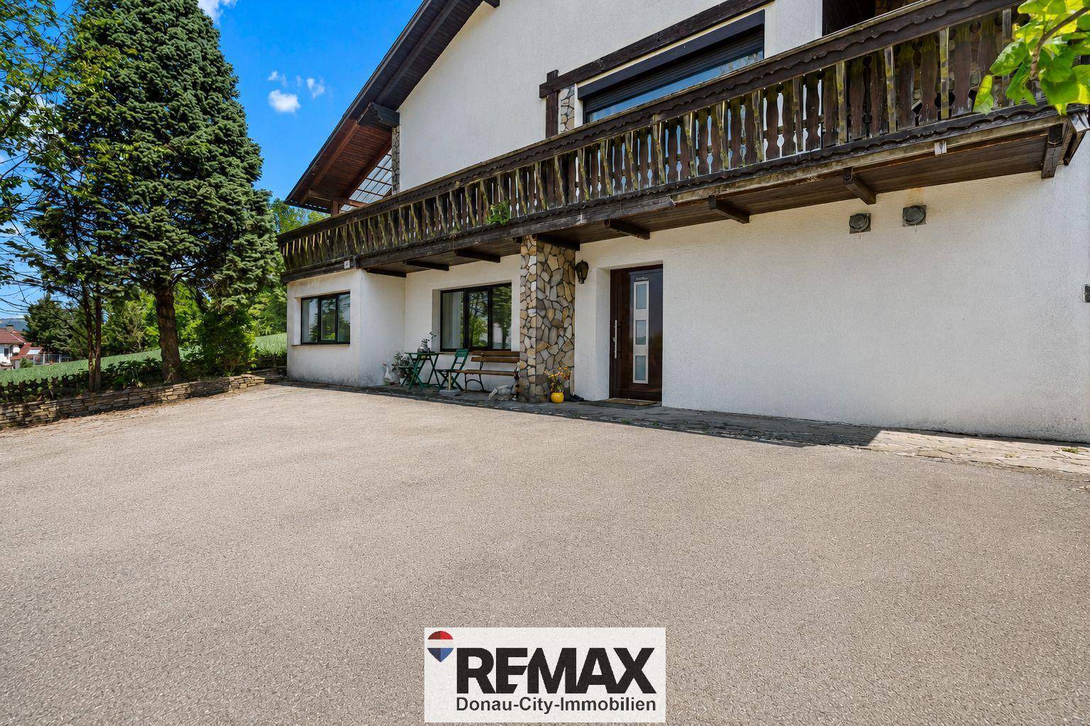 Außenansicht des Hauses mit großem Vorplatz und traditionellem Holzbalkon.