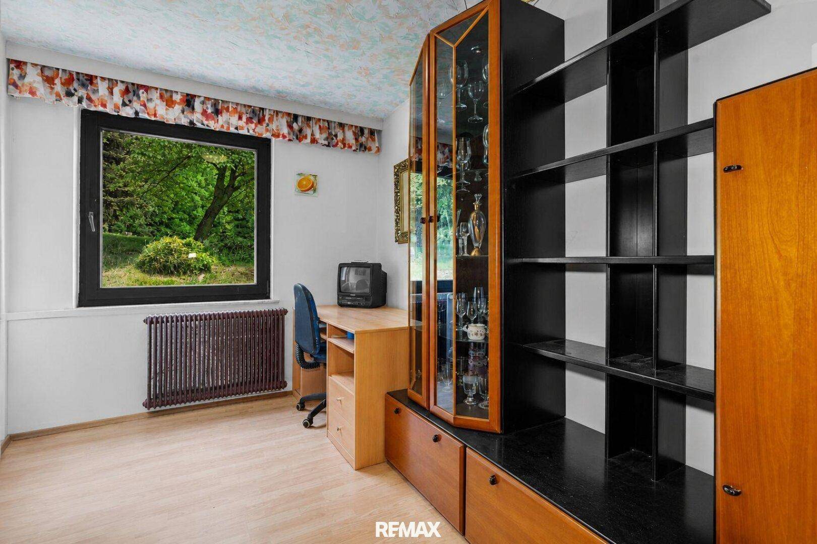 Arbeitszimmer mit Holzboden, großem Fenster und Blick ins Grüne.