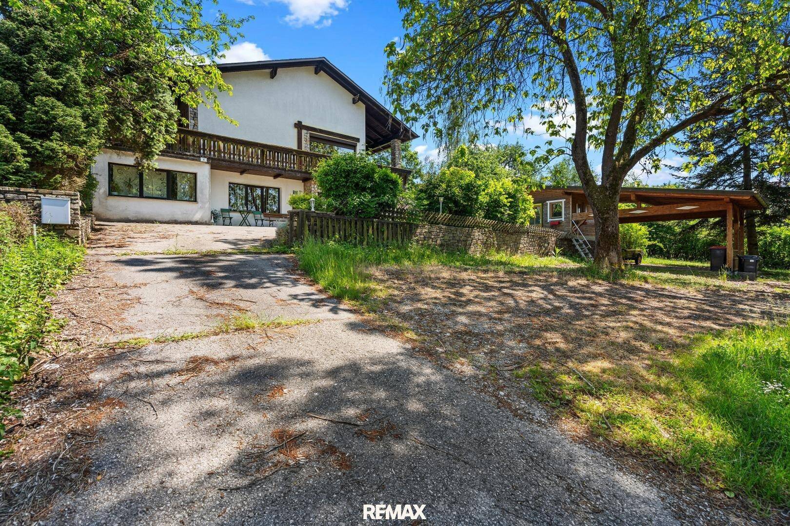 Geräumiges Landhaus mit Balkon und großer Auffahrt, umgeben von Bäumen.