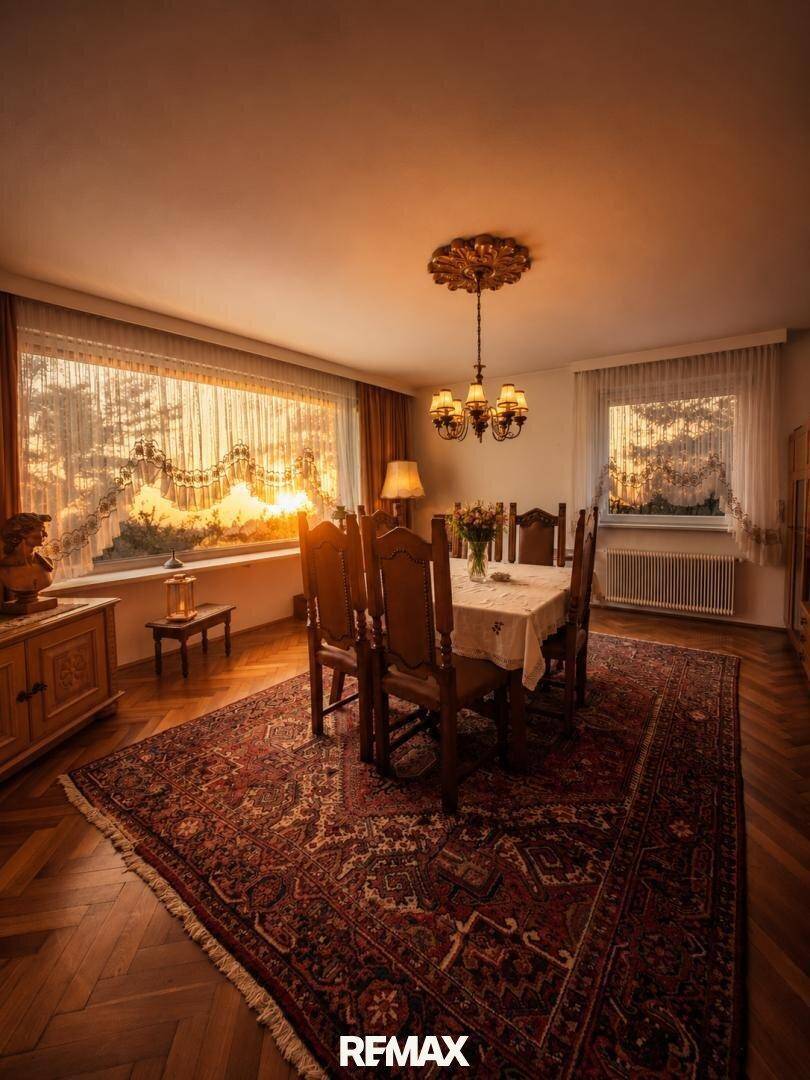 Traditionelles Esszimmer mit großem Holztisch, Kronleuchter und Blick auf den Sonnenuntergang.