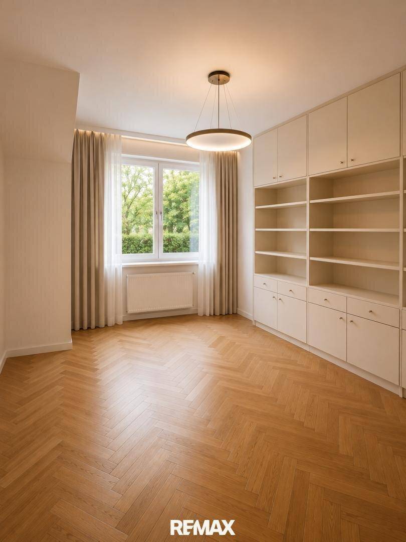 Heller Raum mit Fischgrätparkett und maßgefertigten Einbauschränken, ideal als Büro oder Schlafzimmer.