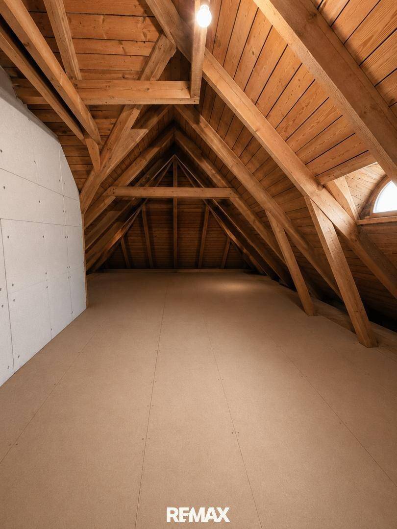Ausbaufähiger Dachboden mit sichtbaren Holzbalken und Dachfenster für zukünftige Nutzung.