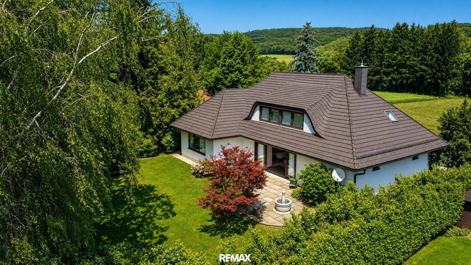 Idyllischer Gartenbereich mit gepflegtem Rasen, Bäumen und einer Terrasse am Haus.