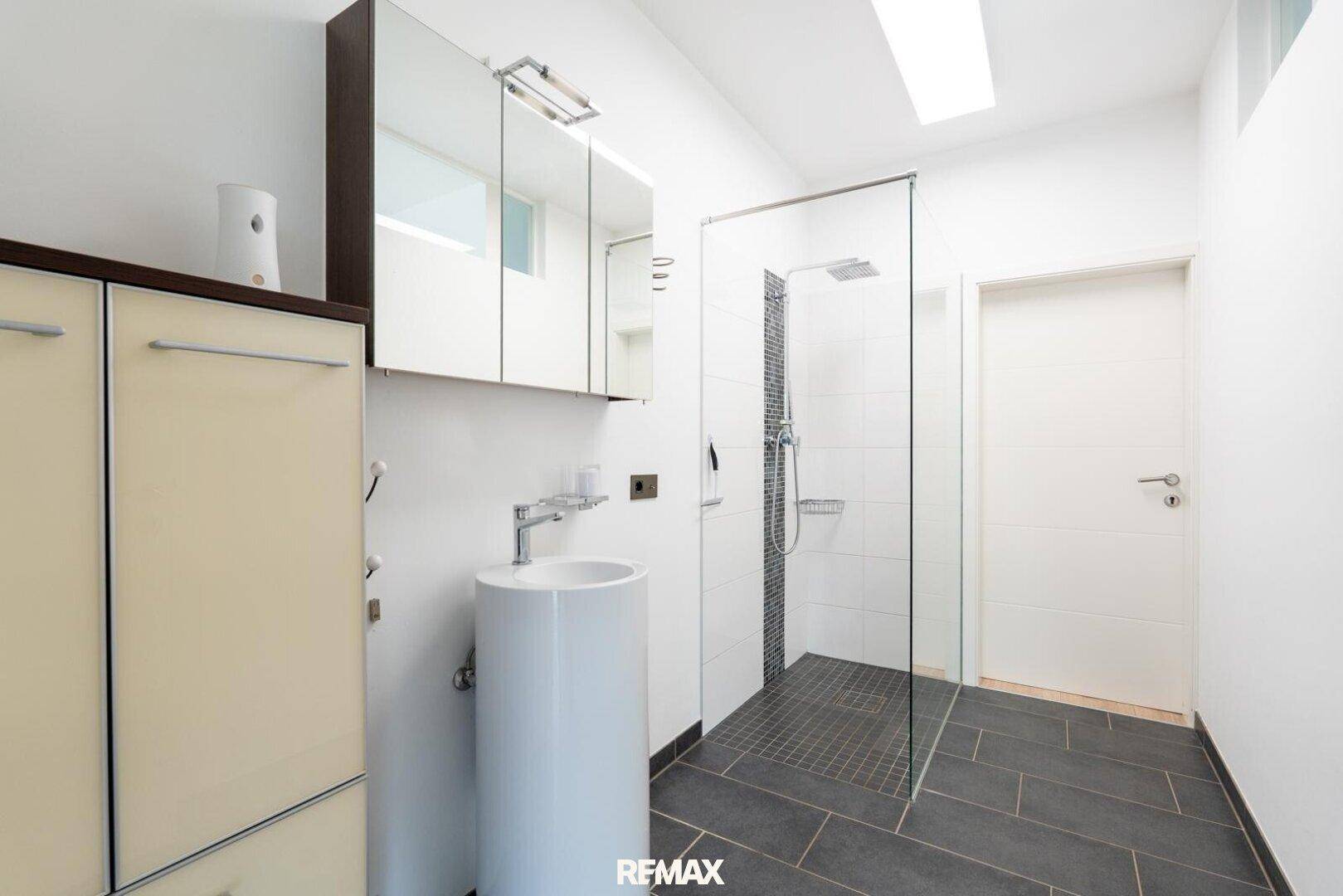 Modernes Badezimmer mit ebenerdiger Dusche, Standwaschbecken und Spiegelschrank.