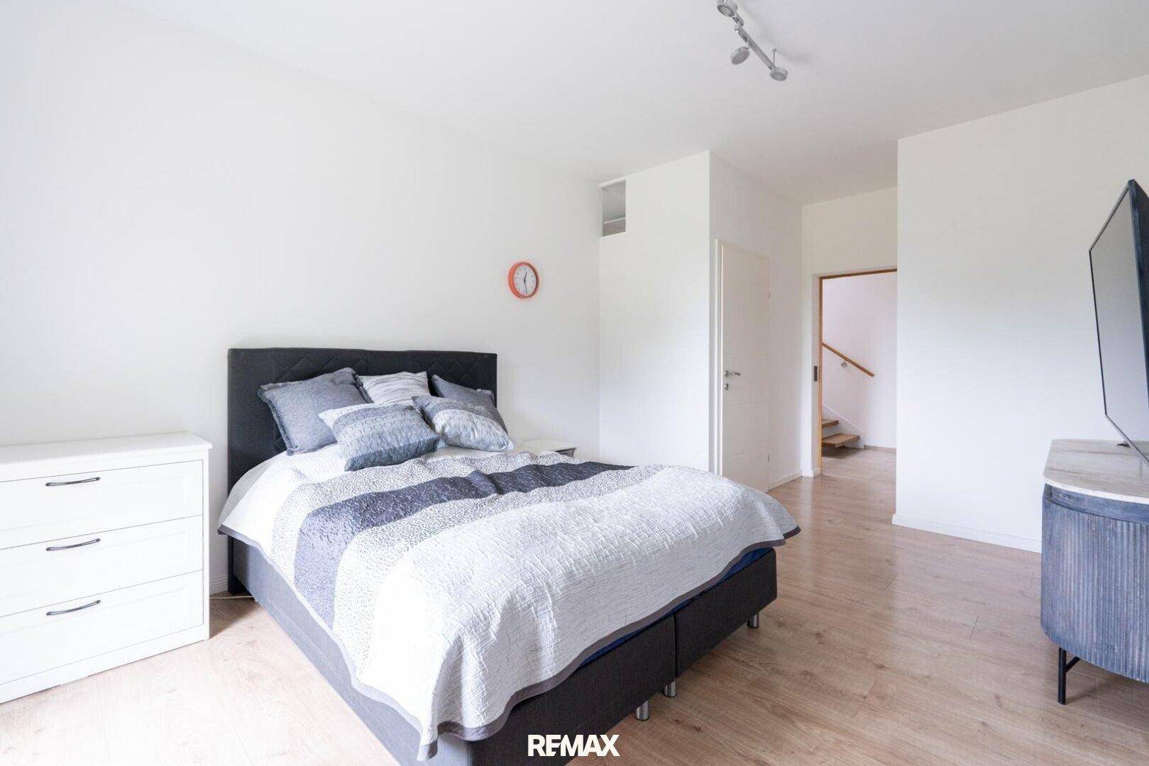 Gemütliches Schlafzimmer mit Doppelbett, Kommode und hellem Laminatboden.