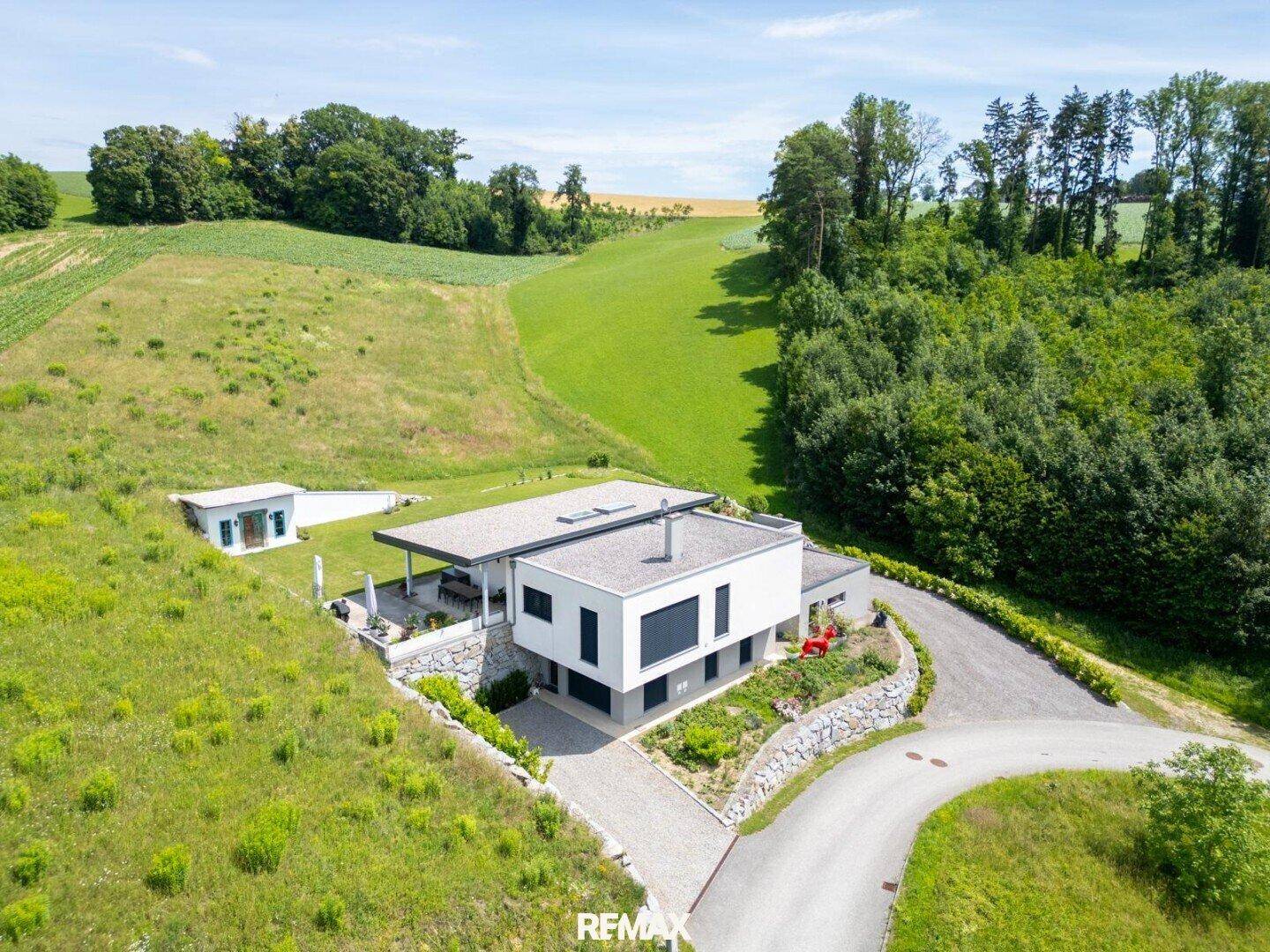 Luftaufnahme des modernen Hauses mit großem Grundstück und umliegender Natur.