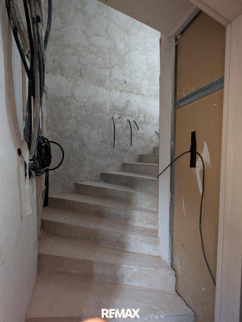 Treppenhaus im Rohbau mit Betonstufen und sichtbaren Installationen.