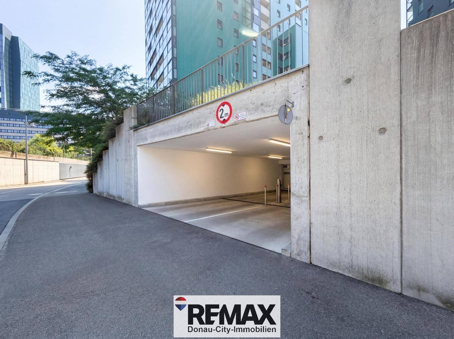 Einfahrt zur Tiefgarage mit Höhenbegrenzung und moderner Betonarchitektur.