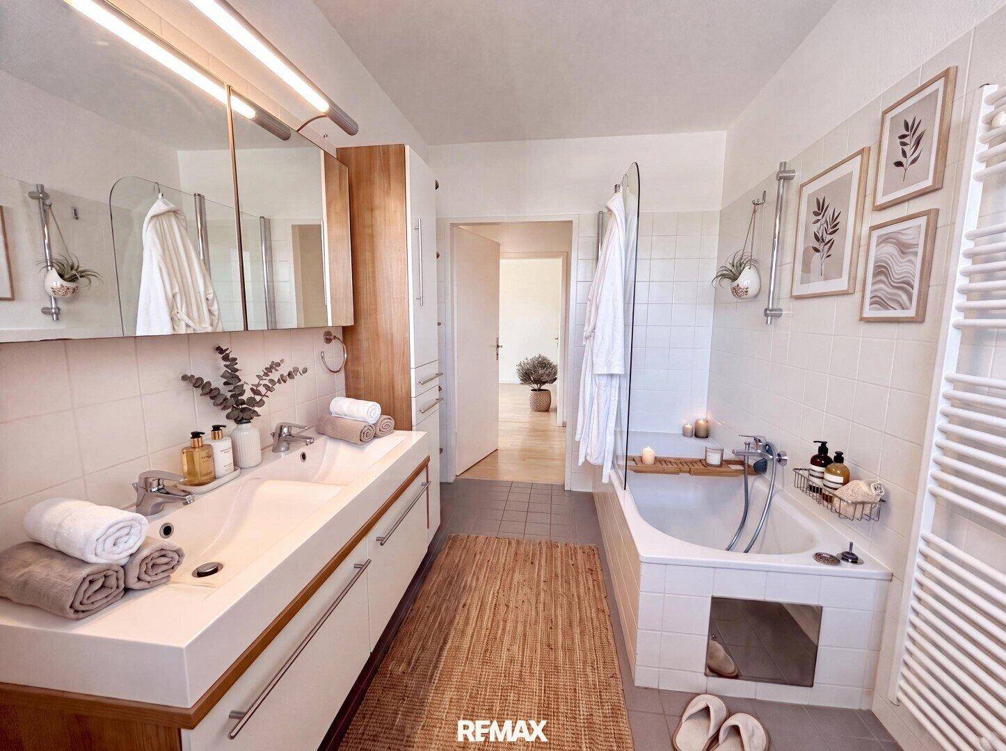 Modernes Badezimmer mit Doppelwaschbecken, Badewanne und weiß gefliesten Wänden.