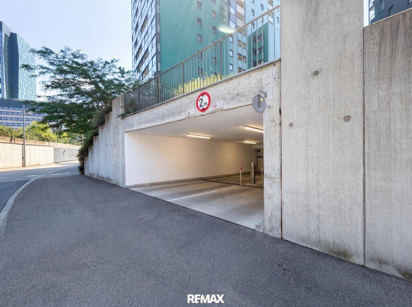 Eingang zu einer Tiefgarage mit Höhenbegrenzung und moderner Betonarchitektur.