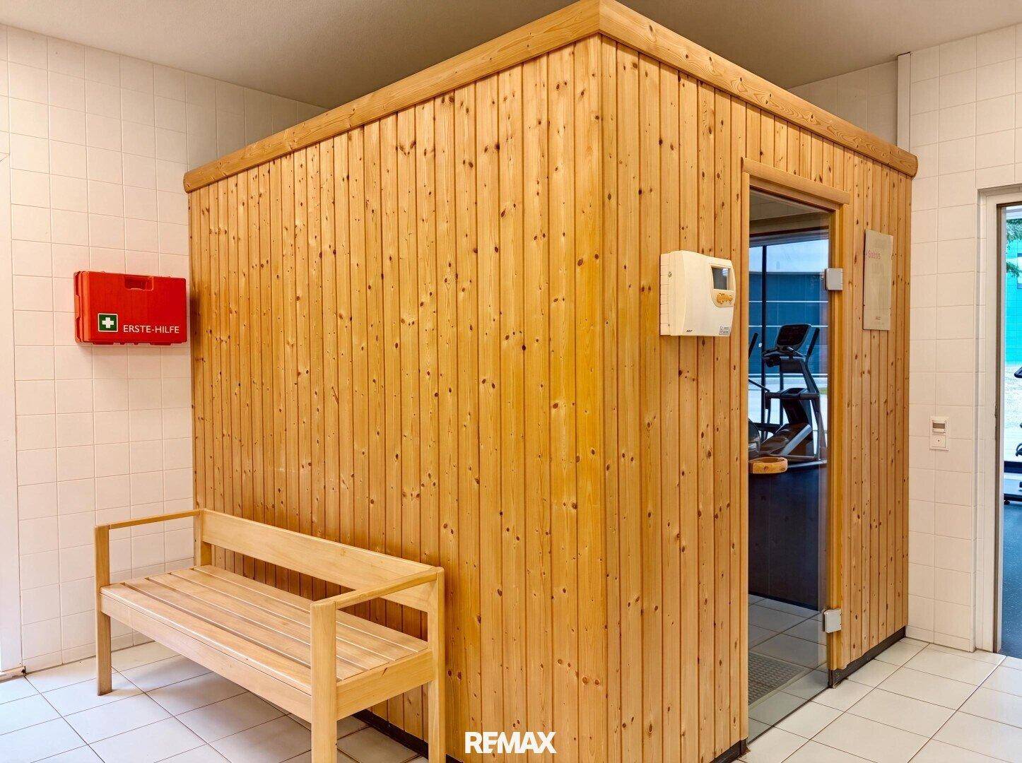 Eine holzvertäfelte Sauna mit Sitzbank und Glastür, Teil eines Wellnessbereichs.