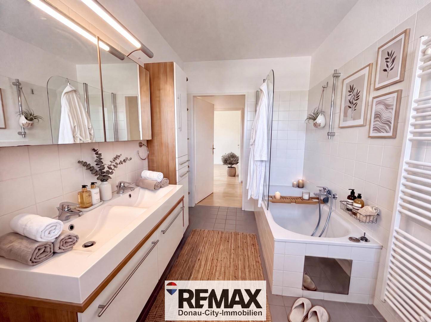 Modernes Badezimmer mit Doppelwaschbecken, Badewanne und hellen Fliesen.