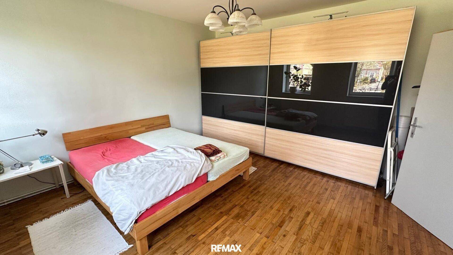 Schlafzimmer mit Doppelbett, Holzfußboden und großem Schiebetürenschrank.