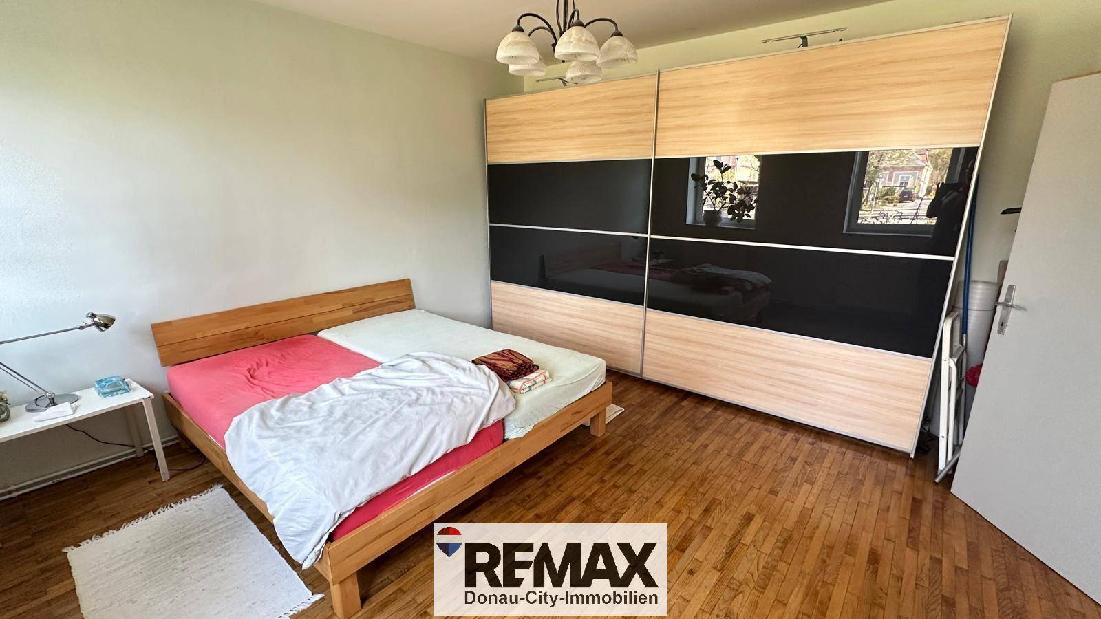 Schlafzimmer mit Holzbett und großem Schiebetürenschrank, bietet viel Stauraum.