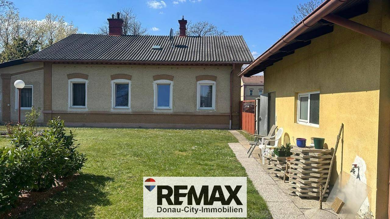 Ansicht des Wohnhauses und eines Nebengebäudes mit gepflegtem Rasen und Gartenbereich.