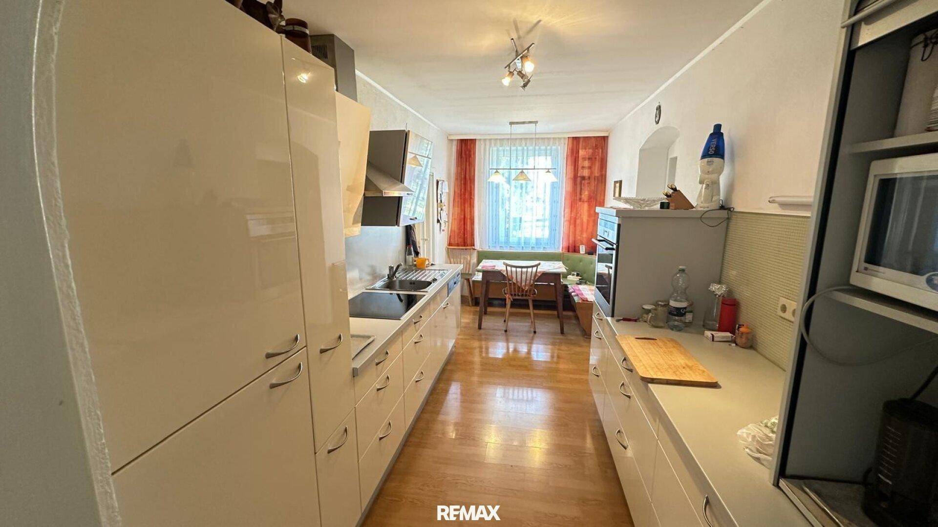 Geräumige Küche mit modernen Einbauschränken und einem Essbereich am Ende des Raumes.