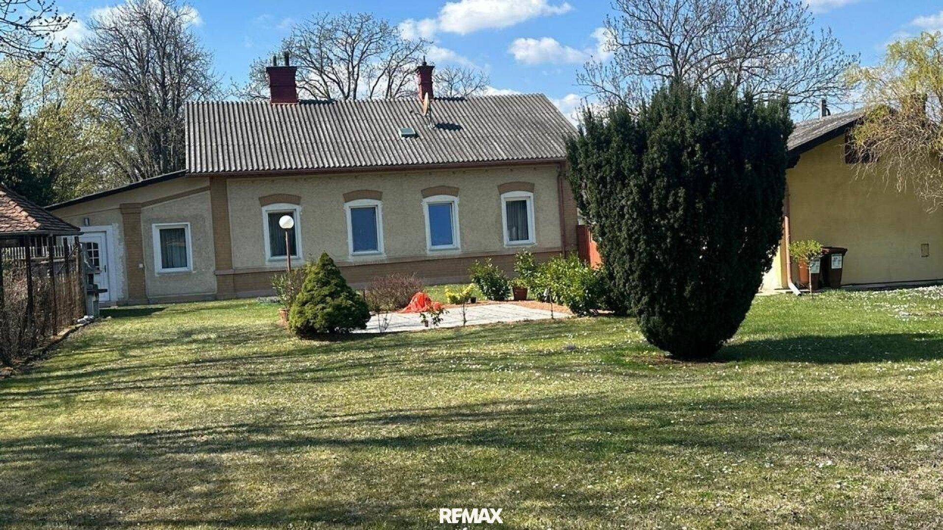 Ansicht des Hauses vom Garten aus, mit Rasenfläche und Ziersträuchern.