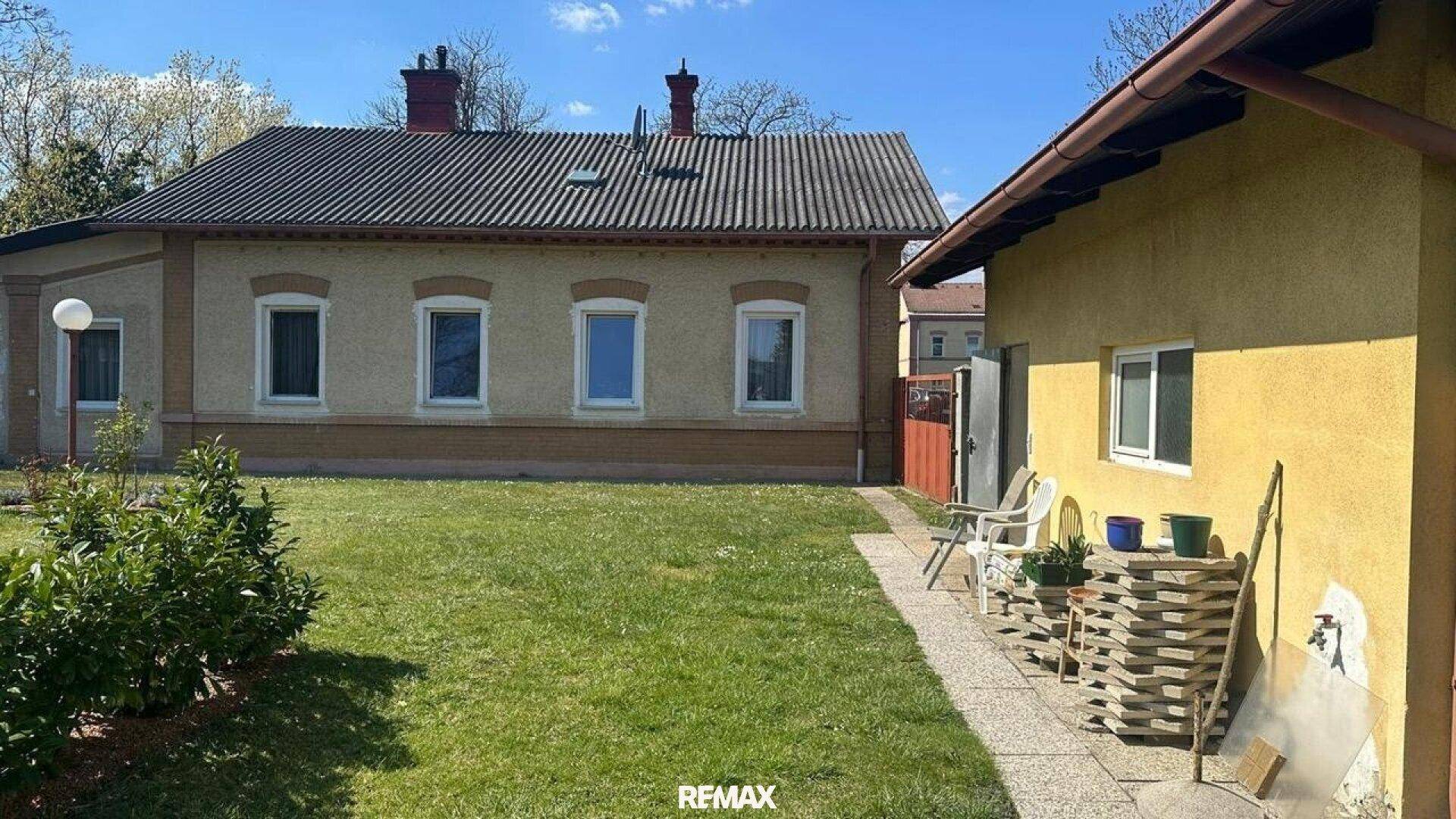 Großer Gartenbereich mit Rasenfläche und einem Nebengebäude neben dem Haupthaus.