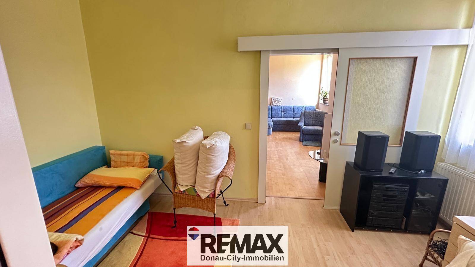 Wohnzimmer mit Sofa, Schiebetür und Blick in einen weiteren Wohnbereich.