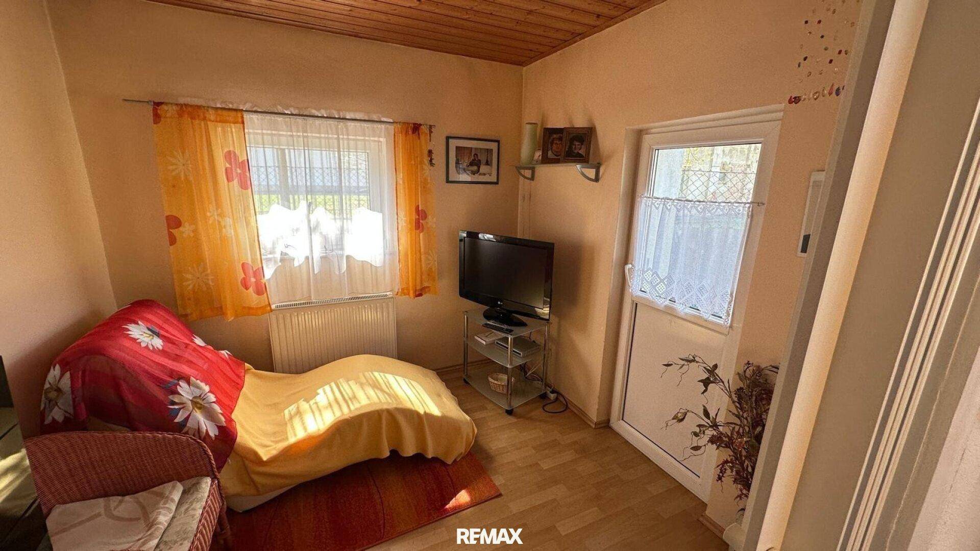 Gemütliches Schlafzimmer mit Holzboden, Fenster und einer Tür zum Außenbereich.