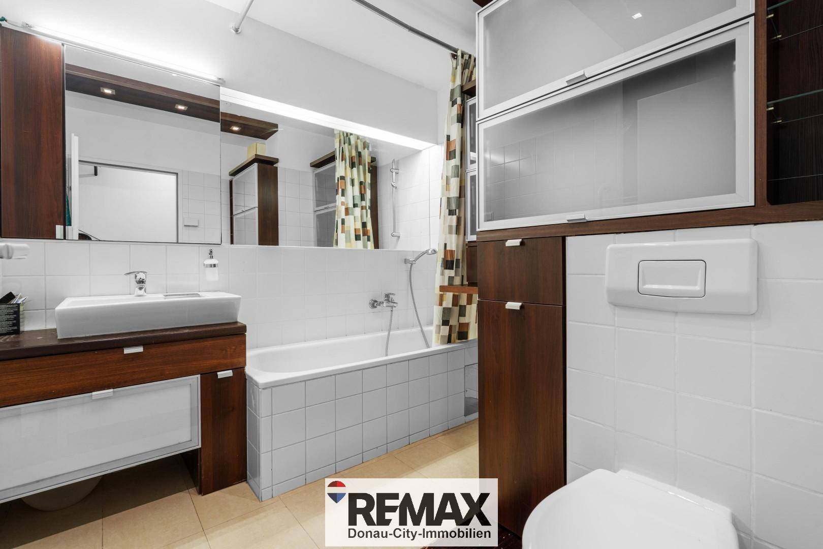 Gefliestes Badezimmer mit Badewanne, Waschbecken und Spiegelschrank.