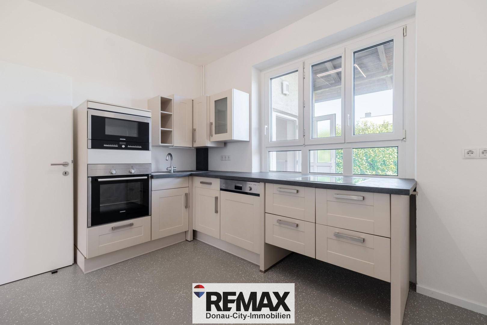 Funktionale Küche mit Einbauschränken, Backofen, Geschirrspüler und großem Fenster.