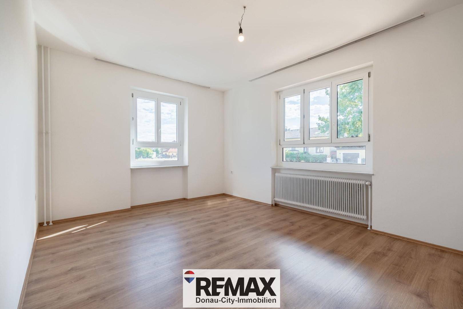 Helles Zimmer mit Laminatboden und zwei Fenstern, ideal als Schlaf- oder Arbeitszimmer.