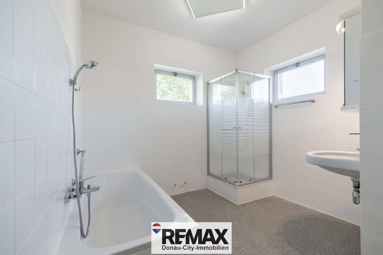 Modernes Badezimmer mit Badewanne, Duschkabine und zwei kleinen Fenstern.