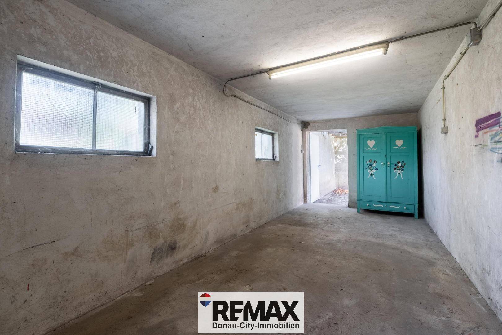 Garage mit Betonboden, Fenstern und einem Schrank für zusätzlichen Stauraum.
