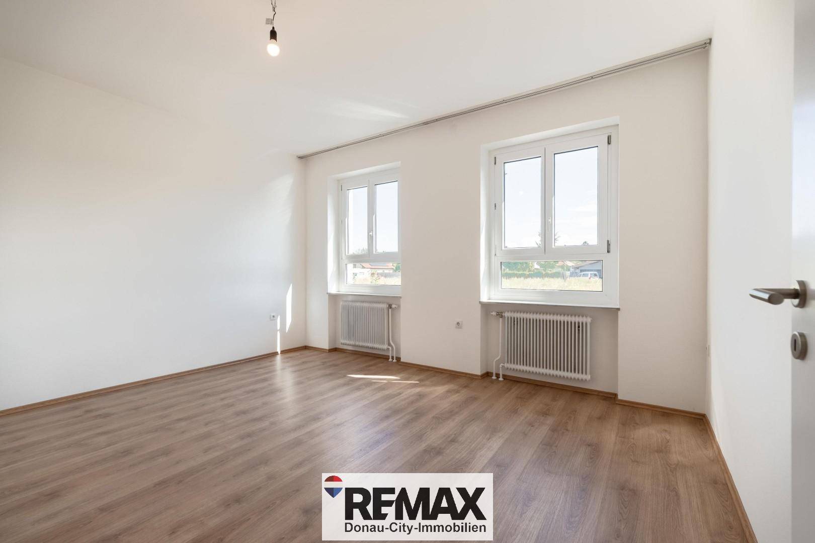 Helles Zimmer mit Laminatboden und zwei Fenstern, geeignet als Schlaf- oder Kinderzimmer.