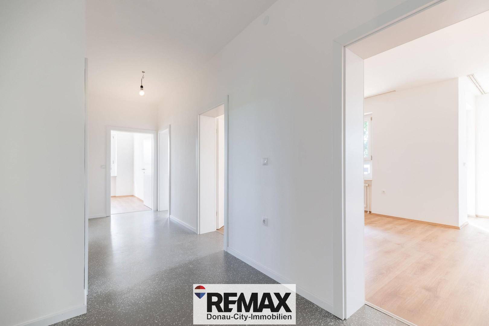 Geräumiger Flur mit grauem Boden, der verschiedene Zimmer miteinander verbindet.