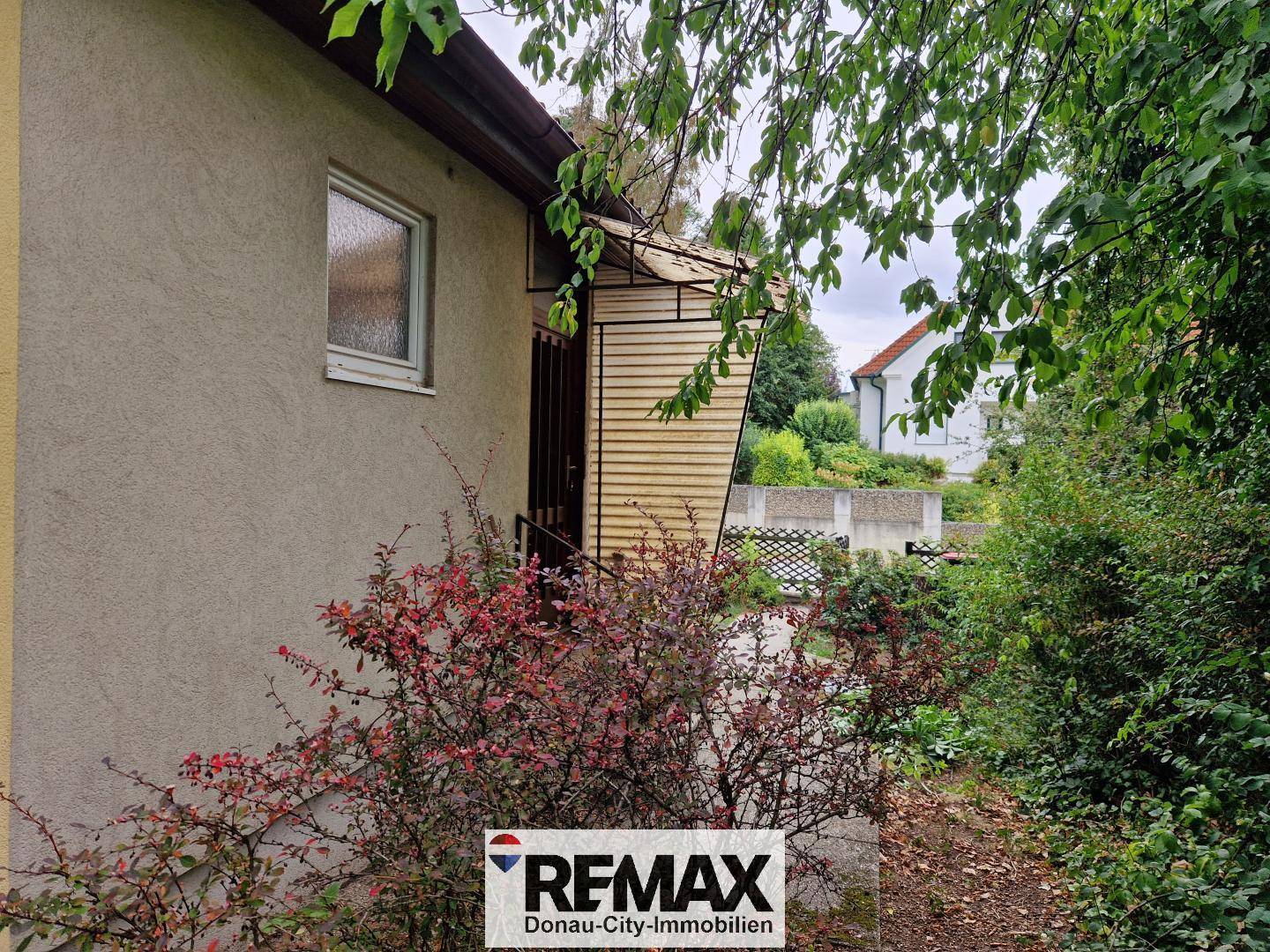 Seitenansicht des Hauses mit einem überdachten Eingangsbereich und Sträuchern.