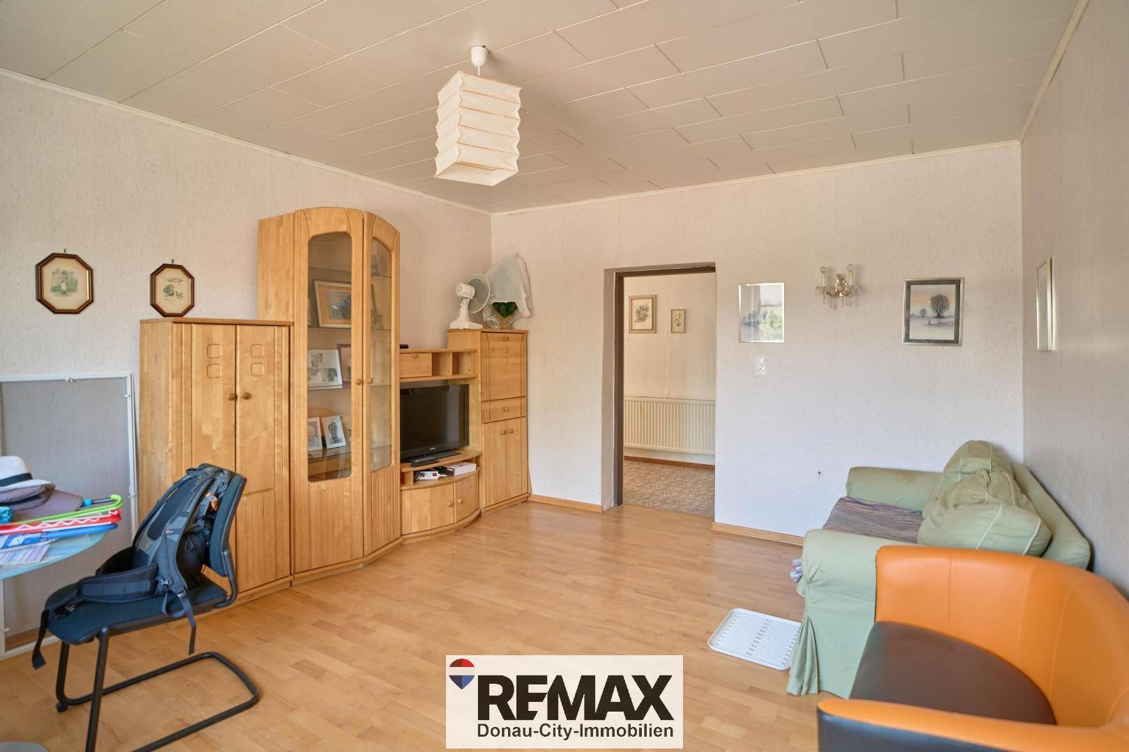 Geräumiger Raum mit Holzmöbeln, Sofa und Durchgang zu weiteren Zimmern.
